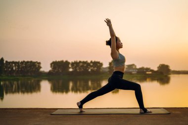 Kız göl kenarında yoga yapıyor.