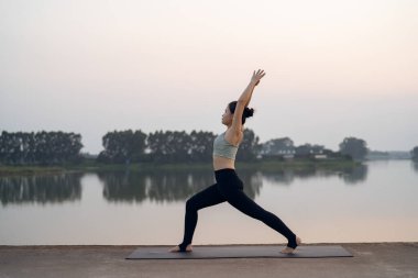 Kız göl kenarında yoga yapıyor.