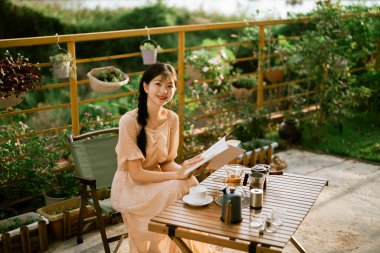 Kız bahçede kitap okuyor.