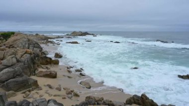 Pasifik Grove, Kaliforniya 'da kayalık bir sahil. Monterey Körfezi' nden dalgalar geliyor, kıyıya çarpıyor. Şarjör yarı hızda. Kamera tamir edildi..