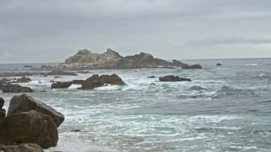 Pasifik Grove, Kaliforniya 'da kayalık bir sahil. Monterey Körfezi' nden dalgalar geliyor, kıyıya çarpıyor. Şarjör yarı hızda. Kamera kilitlendi..