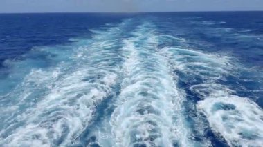 Okyanusta çalkantılı dalgaları gösteren bir yolcu gemisinin arkasından görüntü.