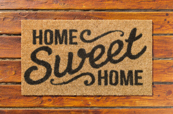 Overhead of Home Sweet Home doormat on the wood plank porch.