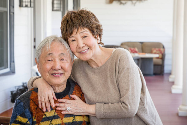 Happy Senior Chinese Couple Pose for Their Portrait On The Porch.