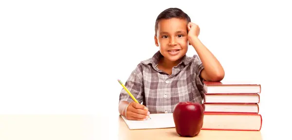 快乐的年轻西班牙裔男孩 书桌前坐着 而苹果则被白色的背景隔开了 — 图库照片