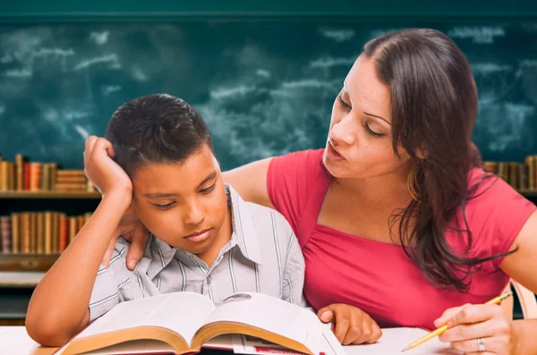 女性のテスターは教室で若いヒスパニックの少年と宿題をする — ストック写真