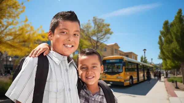 Два Счастливых Латиноамериканских Брата Рюкзаках Возле Школьного Автобуса Кампусе — стоковое фото
