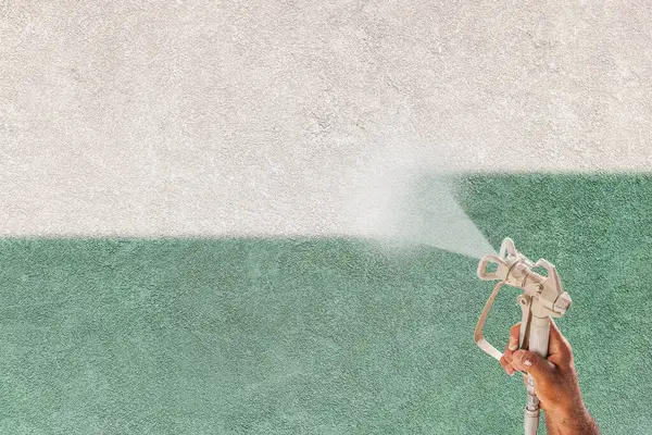 专业喷漆师持有喷枪喷涂白漆涂在Teal Stucco表面 — 图库照片#