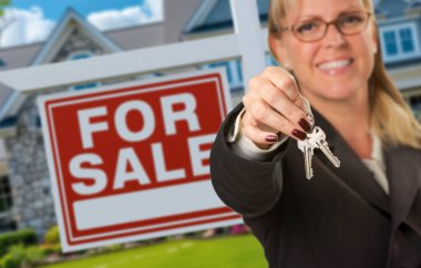 Bayan Emlakçı Ev Anahtarlarını Satılık Tabela ve Yeni Ev 'in önünde sunar. Anahtarlara odaklan..