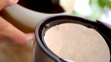 Kahve makinesine su ve kahve dolduran kadın.