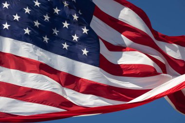 Derin mavi gökyüzüne karşı rüzgarda dalgalanan Amerikan Bayrağı.