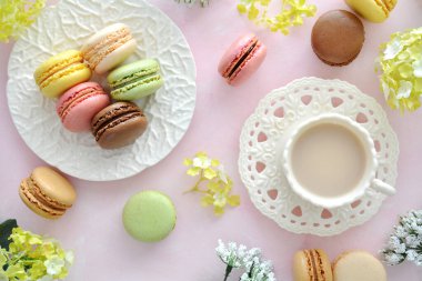 Dainty macaroons with tea in a springtime setting with flowers.  Shot from overhead in flat lay composition.