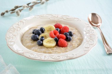 Sağlıklı yulaf ezmesi ve güzel bir kâse içinde taze meyve yatay kompozisyonda soluk su arka planında. Sağlıklı yeme kavramı.