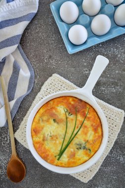 Seramik tavada taze pişmiş ıspanaklı kiş mavi yumurta kasasında yumurtalar, tahta kaşık ve çizgili çay havlusu. Sağlıklı beslenme konsepti. Düz kompozisyonda dikey biçim.