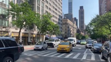 New York 'ta Doğu 66. Cadde' nin kesiştiği yerde kimliği belirsiz insanlar ve sokak trafiği var.