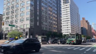 New York 'ta Doğu 66. Cadde' nin kesiştiği yerde kimliği belirsiz insanlar ve sokak trafiği var.