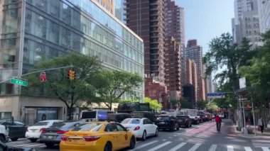 New York 'ta Doğu 66. Cadde' nin kesiştiği yerde kimliği belirsiz insanlar ve sokak trafiği var.