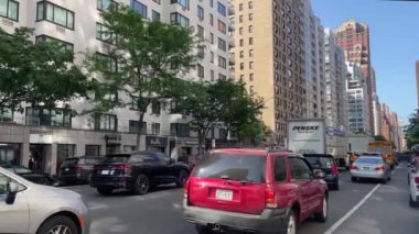 New York 'ta Doğu 66. Cadde' nin kesiştiği yerde kimliği belirsiz insanlar ve sokak trafiği var.