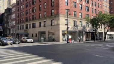 New York 'ta Doğu 66. Cadde' nin kesiştiği yerde kimliği belirsiz insanlar ve sokak trafiği var.