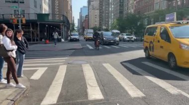 New York 'ta Doğu 66. Cadde' nin kesiştiği yerde kimliği belirsiz insanlar ve sokak trafiği var.