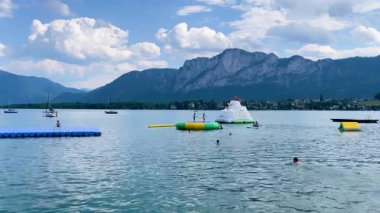 Mondsee, Yukarı Avusturya, 25 Haziran 2024: Ziyaretçiler, Mondsee kasabasındaki popüler bir göl kenti olan Alpenseebad Mondsee 'de güneşli bir yaz gününün tadını çıkarıyorlar