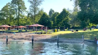 Mondsee, Yukarı Avusturya, 25 Haziran 2024: Ziyaretçiler, Mondsee kasabasındaki popüler bir göl kenti olan Alpenseebad Mondsee 'de güneşli bir yaz gününün tadını çıkarıyorlar