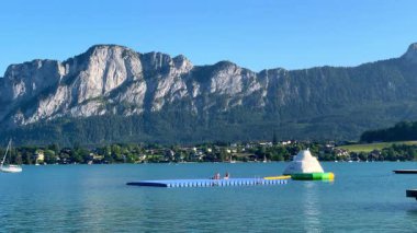 Mondsee, Yukarı Avusturya, 25 Haziran 2024: Ziyaretçiler, Mondsee kasabasındaki popüler bir göl kenti olan Alpenseebad Mondsee 'de güneşli bir yaz gününün tadını çıkarıyorlar