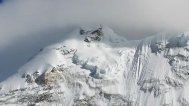 Dağların üzerinde hızla hareket eden bulutlarla kaplı kayalıklarla kaplı Himalayalar.