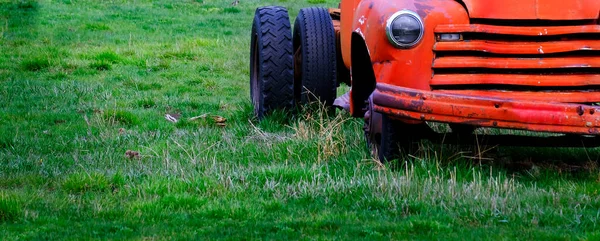 废弃的红色工作卡车被遗弃在一片绿色的农田里 — 图库照片