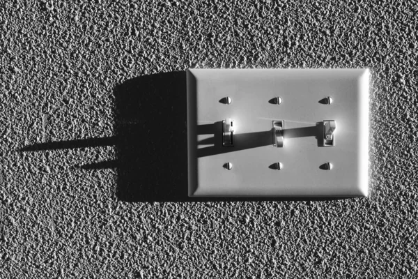 壁に長い暗い影を持ついくつかのライトの光スイッチ — ストック写真