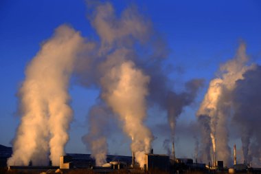 Fabrika bacaları gökyüzüne kirlilik saçıyor dumanı havaya yükseliyor.