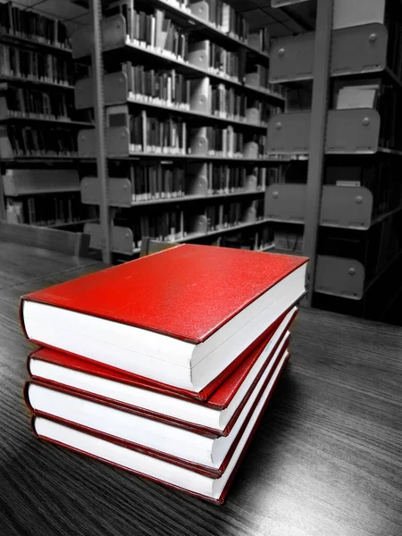 Stack of old red covered books on a desk or table in a library for reading and learning