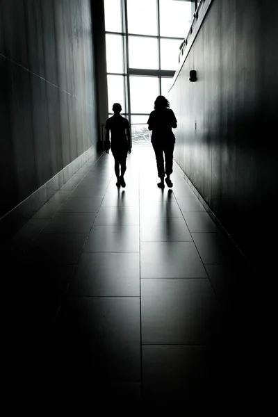 ビジネスビルのホールをシルエットにしたシルエットで歩いている二人 — ストック写真