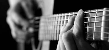 Müzik için parmaklarıyla gitar çalan kişinin yakın plan ayrıntıları