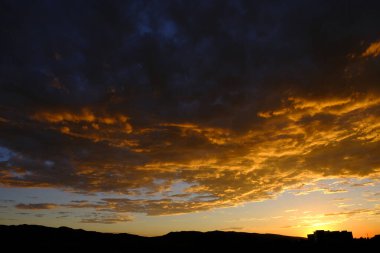 Gün batımı manzarası ya da gökyüzünde gün doğumu dramatik bulutlar dağlar ve bir bina