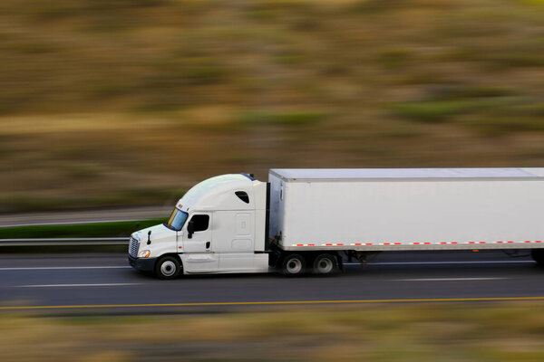 Semi truck and trailer hauling down highway speedy blur blurred blurry