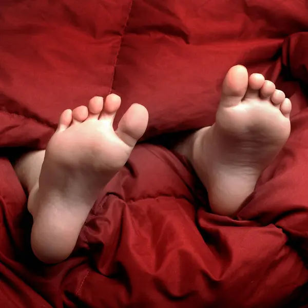 Feet in bed with red blanket person resting bare feet sleep sleeping