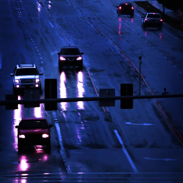 Rainstorm with cars driving in storm on roadway street lamps headlights dark