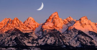 Wyoming Alpen 'deki Teton Dağı' nda sabah güneşi turuncu ve pembe parlıyor. Engebeli dağlarda hilal ay ışığı var.