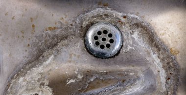 Çelik lavabonun üzerinde su lekeli bir çeşme.