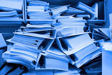 Dosyaları tutan ve dosyaları düzensiz olan dağınık bir ofis.