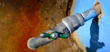 Pas lekeli bir su birikintisine düşen metal faucent.