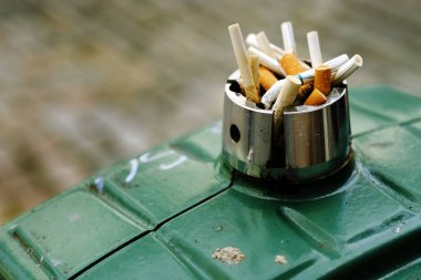 Kül tablasında kirli sigara izmaritlerinin detayları yandı ve çöpe atıldı.