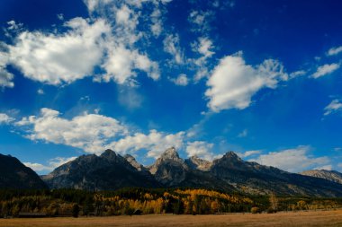 Grand Teton dağlarının ayrıntıları, sonbaharda Wyoming 'deki Tetons sıradağları mavi gökyüzü ve dramatik bulutlarla sonbahar manzarası.