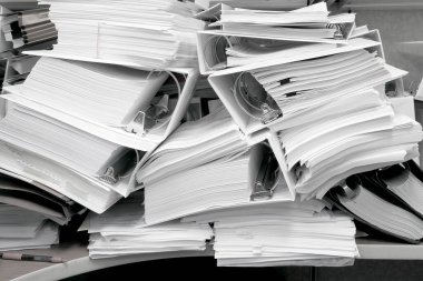 Dosyaları tutan ve dosyaları düzensiz olan dağınık bir ofis.