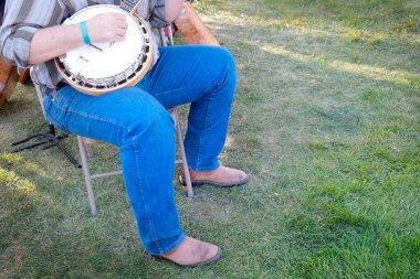 Banço çalan bir adam açık alanda şarkı söyleyerek müzik yapıyor.