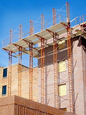 Yeni bina inşa ediliyor ve tuğla döşeme iskelesi olan inşaat alanının ayrıntıları