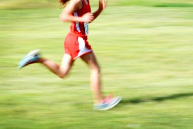 Kırmızı önlük takım yarışması giyip çimde koşan moronla bulanık koşan koşucu.