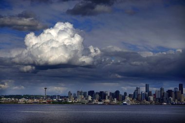 Gökyüzünde büyük bulutlar olan bir feribottan Seattle 'ın manzarası.