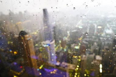 Penceresinde yağmur damlaları olan büyük bir şehirdeki gökdelenlerin ya da gökdelenlerin manzarası